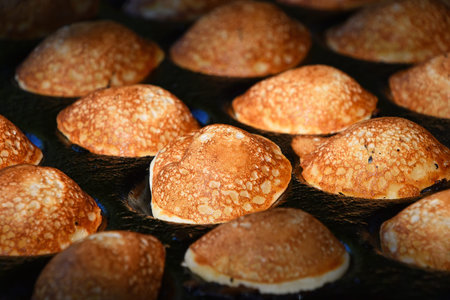 Close up of cooking small round Dutch traditional sweet pancakes, high angle viewの写真素材