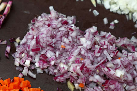 Close up assorted cut and sliced fresh vegetables on black cooking board, high angle viewの写真素材