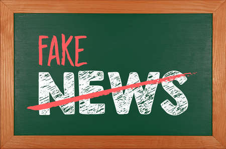 Green school chalkboard blackboard sign in brown wooden frame with chalk written FAKE NEWS wordsの写真素材