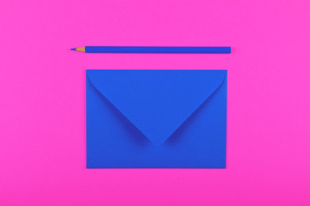 One closed blank indigo blue paper envelope and wooden pencil over vivid magenta pink background,...