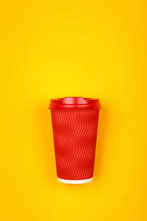 Close up one crimped disposable red paper takeaway coffee cup over vivid yellow background, flat lay, elevated top view, directly aboveの写真素材