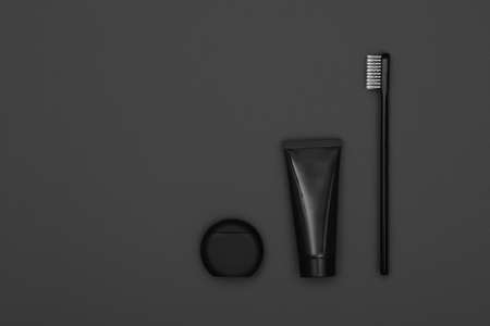 Close up one black toothpaste tube, floss and toothbrush over dark grey background, masculine dental care flat lay, elevated top view, directly aboveの写真素材