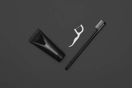Close up one black toothpaste tube, floss and toothbrush over dark grey background, masculine dental care flat lay, elevated top view, directly aboveの写真素材