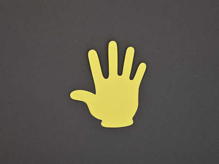 Paper made yellow STOP or HI hand gesture sticker over grey backgroundの写真素材