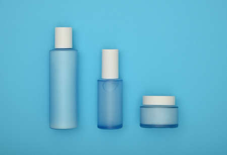 Close up set of three cosmetic skin care cream, lotion and tonic bottles over pastel blue background, elevated top view, directly aboveの写真素材