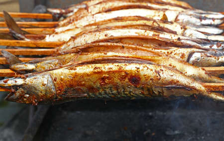 Close up cooking several bonito mackerel fishes on wooden skewer grill, high angle viewの写真素材