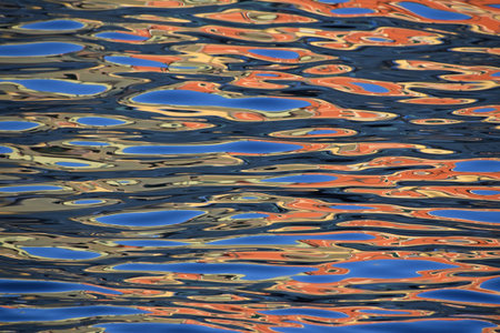 Abstract background of vivid colorful blue and orange water ripples and waves, reflection at sea...