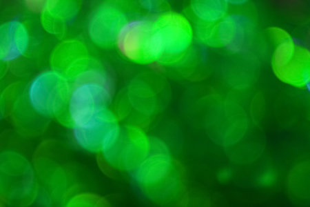 Colorful vivid green bokeh defocused blurred lights and sparkles abstract backgroundの写真素材