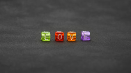 Close up word LOVE of colorful multicolor cube shape plastic beads over black background, low angle...