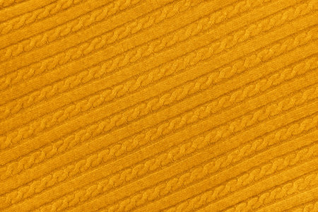 Close up background texture of warm yellow cable knitted wool jersey fabric sweater with row braid...