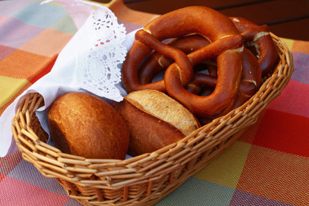 Close up several traditional German pretzel bread knots and fresh buns in bread basket on table,...