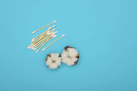 Close up feminine hygiene and beauty care flat lay of ear bud swabs and cotton flowers over blue background, elevated top view, directly aboveの写真素材