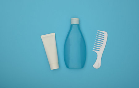 Close up one bottle of shower gel or shampoo, conditioner or lotion and hair comb over blue...
