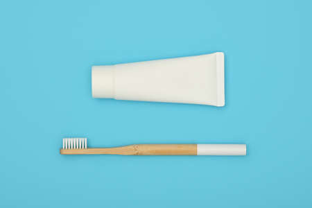 Close up one white toothpaste tube and natural wooden bamboo toothbrush on blue background, flat lay, elevated top view, directly aboveの写真素材