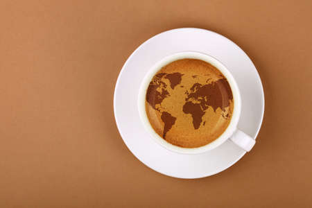 Close up white cup on saucer, full of espresso coffee with world map on froth crema, over background of brown paper with copy space, elevated top view, directly aboveの写真素材