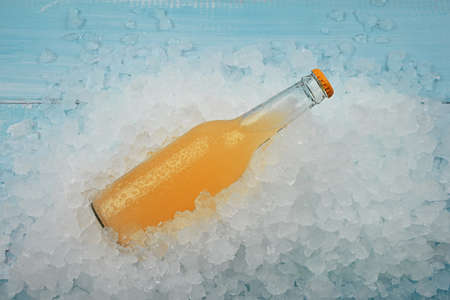 Close up one glass bottle of cold orange cocktail on crushed ice at retail display, high angle viewの写真素材