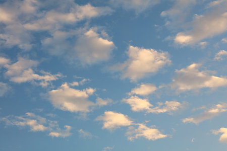 Beautiful cloudscape with bright white and pink clouds over blue sky at early sunset or late...