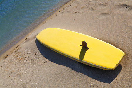 Close up one yellow surfing board on sand sea beach, high angle view, personal perspective