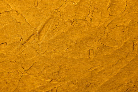 Close up vivid golden yellow abstract background texture of uneven grunge surface with brushstrokes...