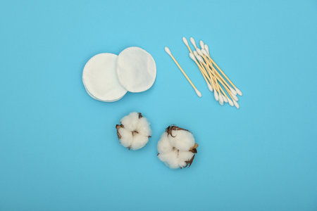 Close up feminine hygiene and beauty care flat lay of makeup sponges, ear bud swabs and cotton flowers over blue background, elevated top view, directly aboveの写真素材