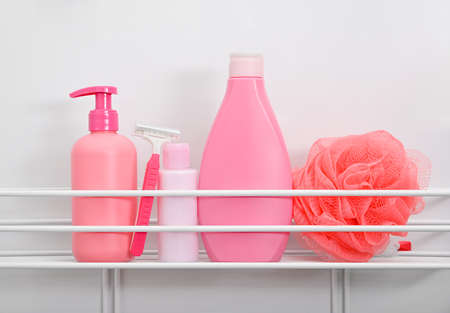 Close up pink bottles of beauty care and personal hygiene products, woman shaving set, on bath shelf over white bath background, low angle viewの写真素材