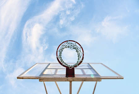 Close up empty basketball basket hoop at outdoors court over background of blue sky, low angle view, directly belowの写真素材