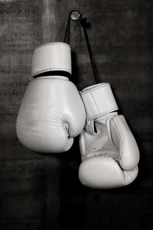 Close up pair of white leather boxing gloves hanging over black wall with copy spaceの写真素材