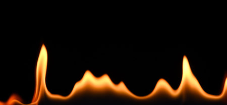 Close up line of fire flames pattern isolated on black background, low angle, side viewの写真素材