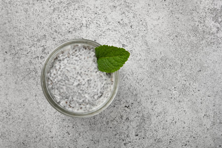 Close up one transparent glass jar of chia seeds pudding dessert with coconut milk on table, elevated top view, directly aboveの写真素材