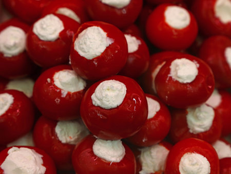 Close up pickled red hot Italian pepperoncini round pepper stuffed with fresh white cheese on retail display, high angle viewの写真素材