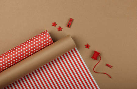 Close up packing and wrapping Christmas gifts with red and brown paper, table top view, flat layの写真素材
