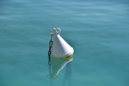 One white navigation safety boundary marker buoy in teal blue sea water, copy spaceの写真素材