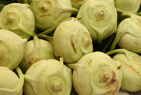Close up fresh green kale turnip kohlrabi root cabbage at retail display of farmer market, high angle viewの写真素材