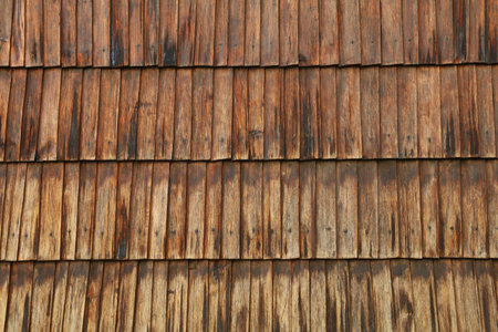 Close up view of overlapping old wooden shingles forming a textured surface on the exterior of a building, showcasing weathering and natural wood grainの写真素材