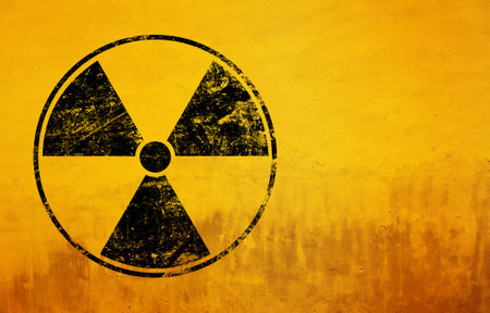 Black radioactive hazard warning sign painted over grunge yellow background with copy spaceの写真素材