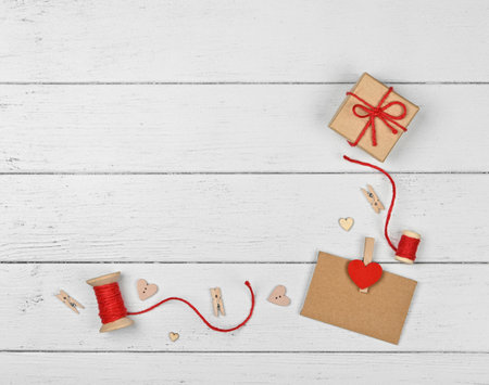 Preparing Valentine gifts, brown paper box, hearts, twine, clothespins and paper note on white wooden table background, close up flat lay, elevated top view, directly aboveの写真素材