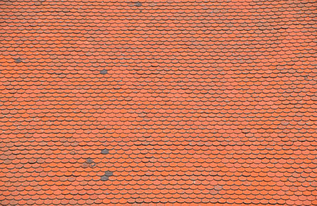 Uniform rows of old orange roof tiles create a visually appealing pattern, illuminated by natural sunlight, showcasing the craftsmanship and architectural detail of a traditional roofing styleの写真素材
