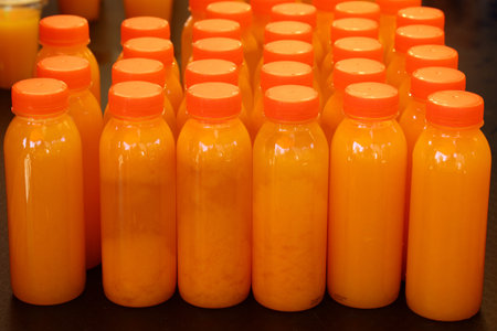 Close up many plastic bottles of fresh orange juice at retail display, high angle viewの写真素材