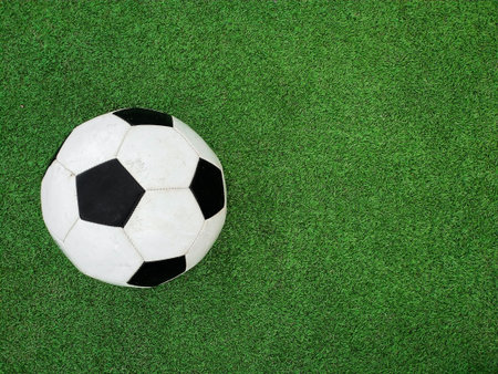 Close up one black and white football ball over green artificial turf of soccer field pitch with white marking lines, elevated, high angle view, directly aboveの写真素材
