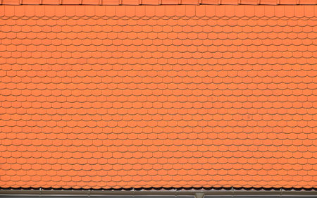 Orange red roof tiles forming a classic European architectural texture, showing a repeating pattern...