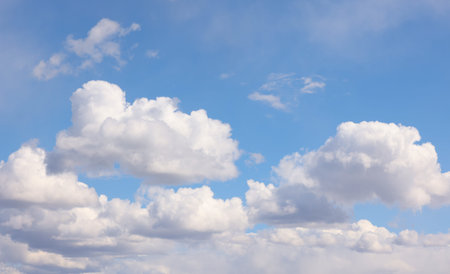 Blue sky filled with soft white cumulus clouds, evoking calm, open space and clear weatherideal...