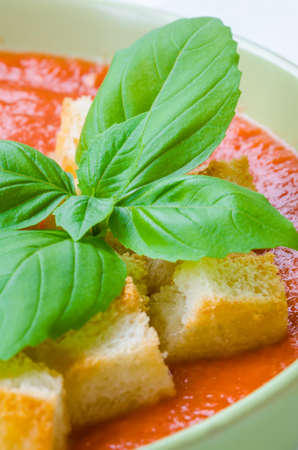 Traditional Spanish cold tomato soup gazpacho with basil and croutons on wooden tableの写真素材