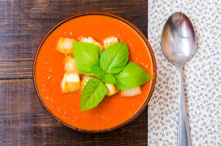 Traditional Spanish cold tomato soup gazpacho with basil and croutons on wooden tableの写真素材