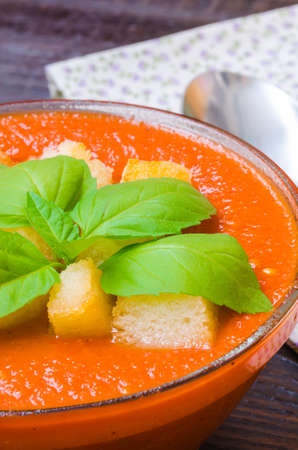 Traditional Spanish cold tomato soup gazpacho with basil and croutons on wooden tableの写真素材