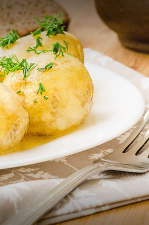 Traditional Ukrainian food boiled new potatoes with butter and dill on wooden tableの写真素材
