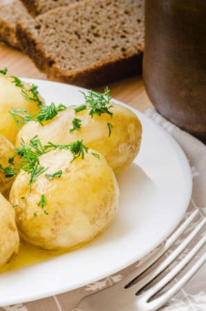 Traditional Ukrainian food boiled new potatoes with butter and dill on wooden tableの写真素材
