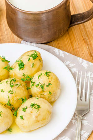 Traditional Ukrainian food boiled new potatoes with butter and dill on wooden tableの写真素材