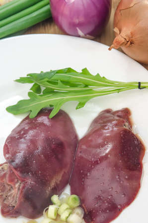 Raw chicken liver with vegetables on wooden backgroundの写真素材