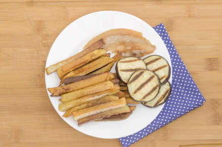 Fries potatoes with grilled eggplant on wooden backgroundの写真素材