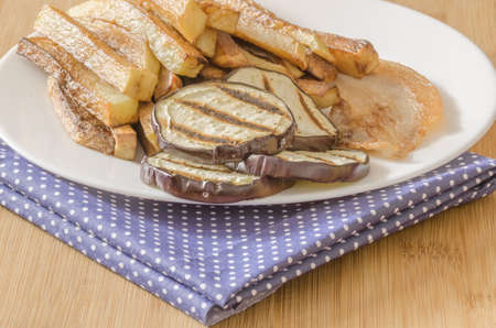 Fries potatoes with grilled eggplant on wooden backgroundの写真素材